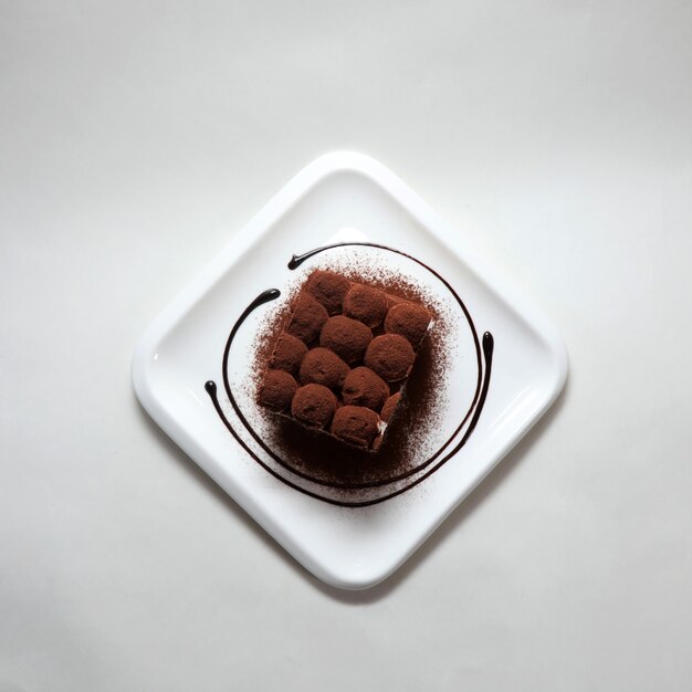 High angle shot of delicious tiramisu in a white plate on a white background