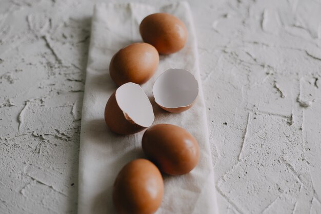 High angle shot of eggs and eggshells on a white towel on the table