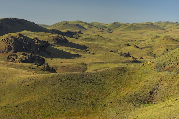 High angle shot of empty grassy hills with a blue sky in the background at daytime