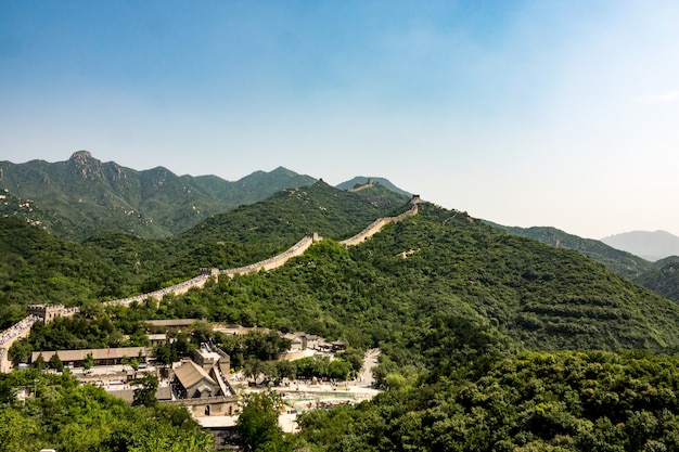 High angle shot of the famous Great Wall of China surrounded by green trees in summer