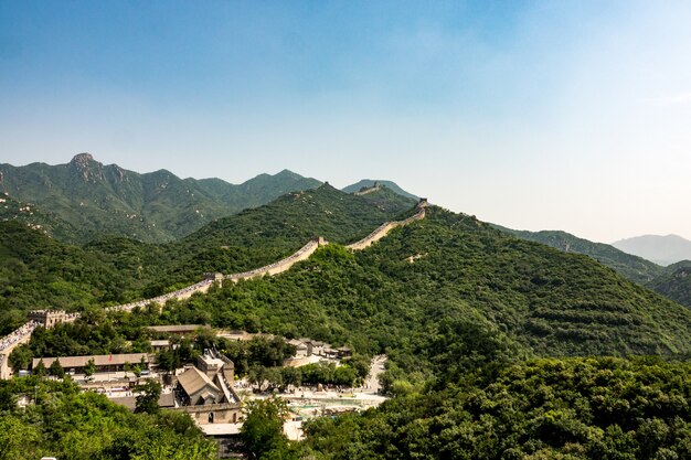 High angle shot of the famous Great Wall of China surrounded by green trees in summer