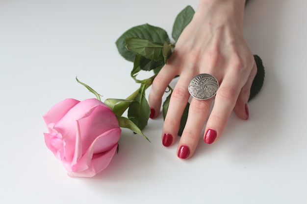 緑の葉とバラの美しい銀の指輪を持つ女性の手のハイアングルショット