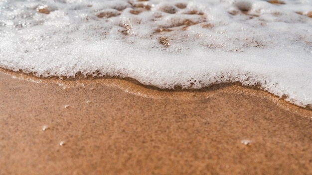 모래 해변을 향해 오는 거품 파도의 하이 앵글 샷