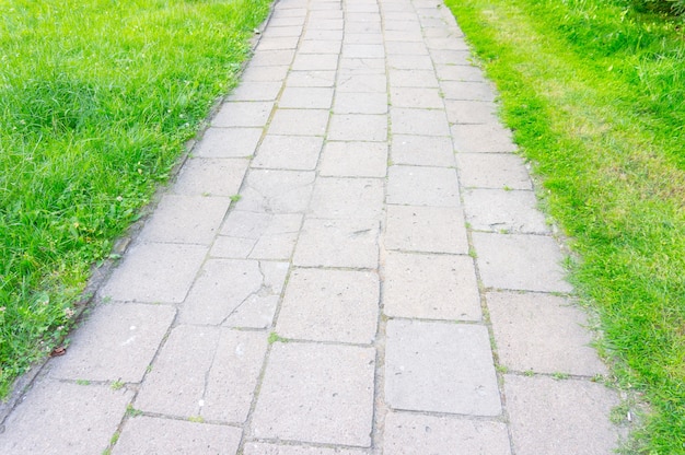 High angle shot of footpath made of stone tiles surrounded by green grass