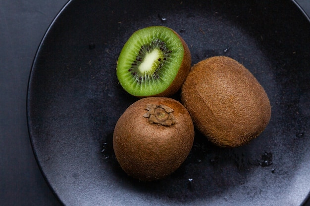 Free photo high angle shot of a fresh kiwi in a black plate