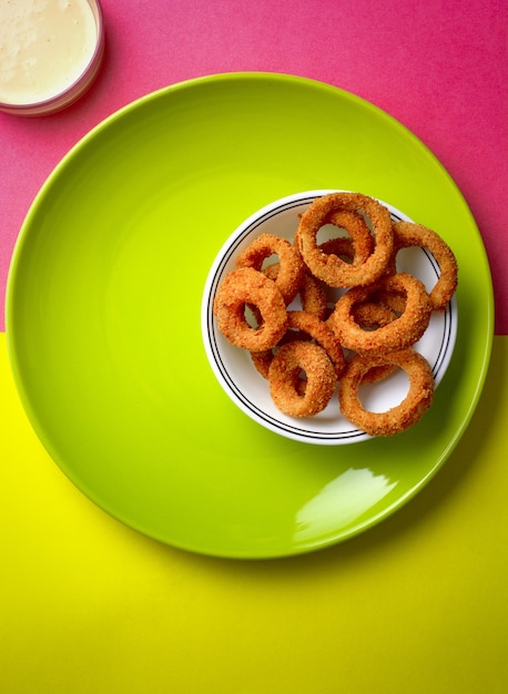 High angle shot of fried onion rings placed on a green plate