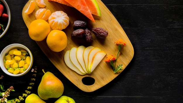 High angle shot of grapes, pears, orange, watermelon and dates on a chopping board