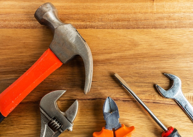 High angle shot of a hammer, a screwdriver and other tools on a wooden surface