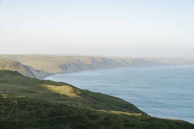 High angle shot of hills covered in the greenery surrounding the ocean