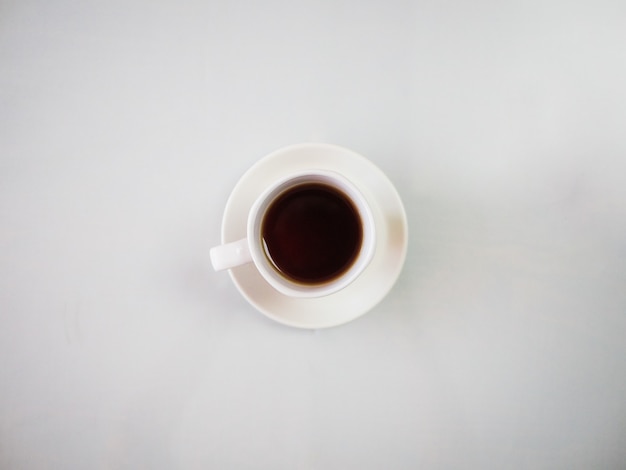 白い皿に置かれた白いカップで熱いお茶のハイアングルショット