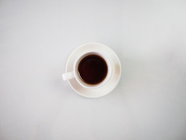 白い皿に置かれた白いカップで熱いお茶のハイアングルショット
