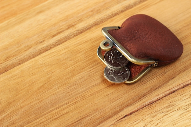 High angle shot of a leather change purse and some coins on a wooden surface