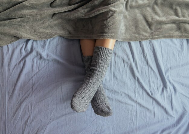 담요 아래에 회색 니트 양말을 신은 여성 다리의 하이 앵글 샷