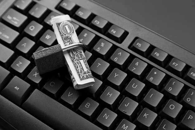 High angle shot of a lock around a dollar bill on a black laptop