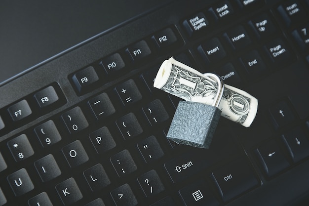 High angle shot of a lock around a dollar bill on a black laptop