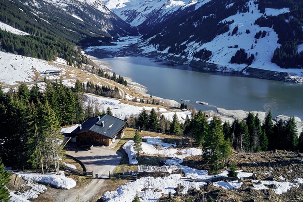 High angle shot of mountains and a river with an isolated house in the forest on the shore