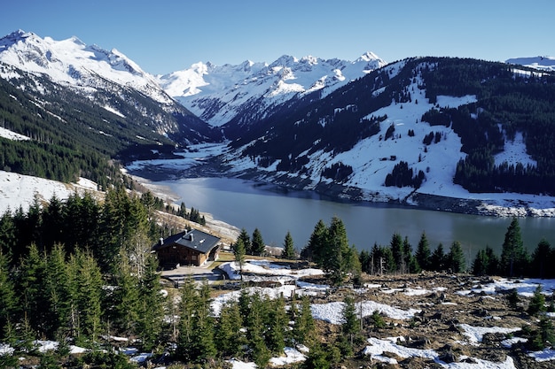 High angle shot of mountains and a river with an isolated house in the forest on the shore