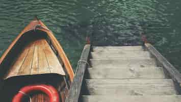 Бесплатное фото Снимок небольшой лодки возле деревянной лестницы в красивом море с высоким углом