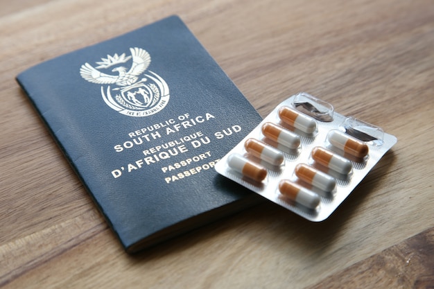 High angle shot of a pack of capsules and a passport on a wooden surface