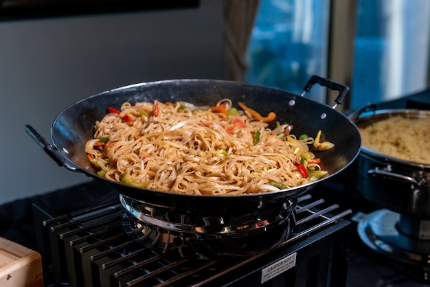 High angle shot of a pan filled with delicious noodles and vegetables in a kitchen