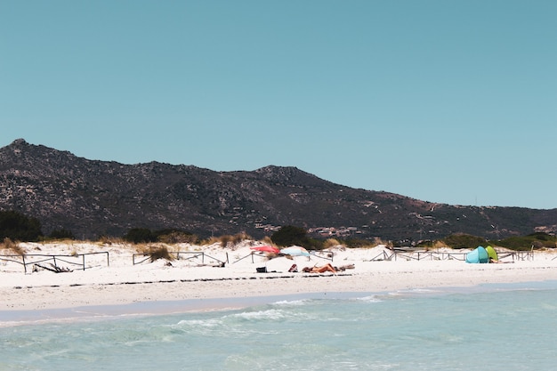 Foto gratuita colpo di alto angolo di persone che si rilassano nella spiaggia di san teodoro, sardegna