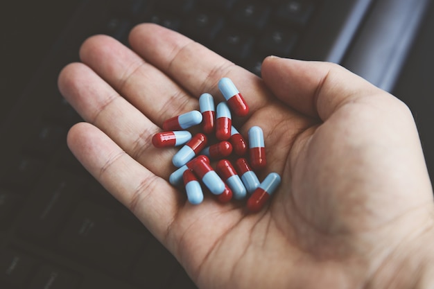 High angle shot of a person holding capsules with a keyboard