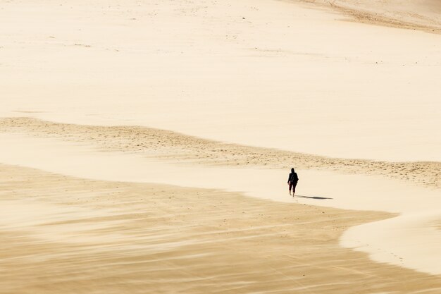 사막의 따뜻한 모래 위에서 맨발로 걷는 사람의 높은 각도 샷