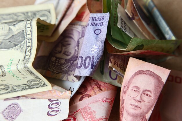 High angle shot of a pile of banknotes from different countries on a wooden surface