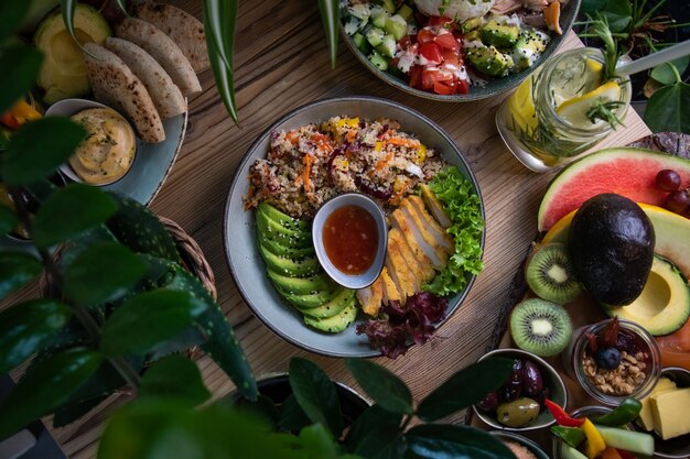 High angle shot of plates of salad and fresh fruits and vegetable on a wooden surface