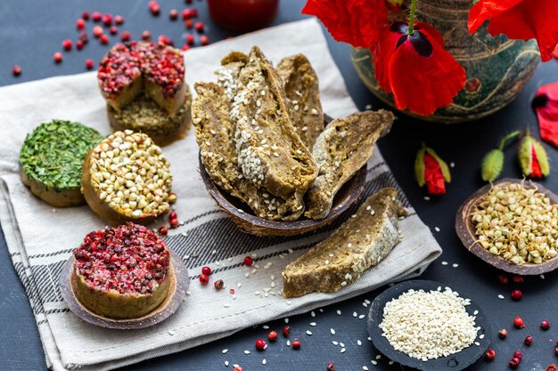 High angle shot of Raw vegan bread with red pepper, buckwheat, poppies on a dark tabletop