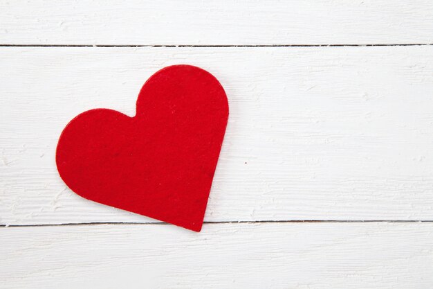 High angle shot of a red paper heart isolated on a white wooden surface