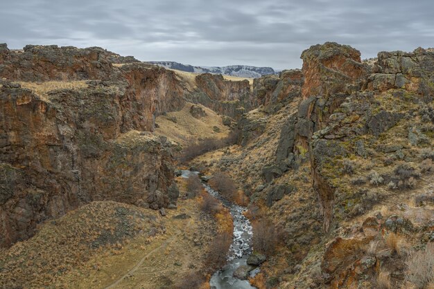 High angle shot of a river in the middle of desert mountains with a cloudy sky