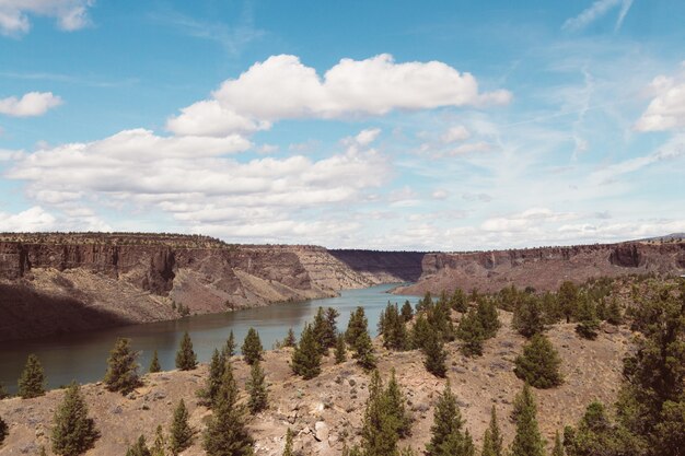 High angle shot of a river surrounded by hills in a deserted area under the bright cloudy sky