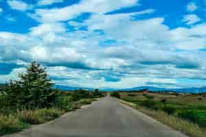 Free photo high angle shot of a road in the valley under the sky with big white clouds