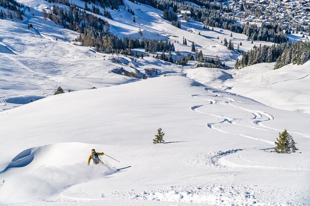High angle shot of a ski resort with ski tracks and a skier going down the slope