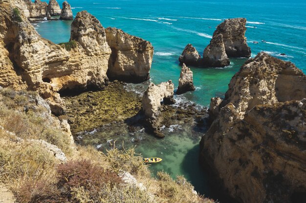 High angle shot of a small boat in the lagoon surrounded by cliffs in the ocean