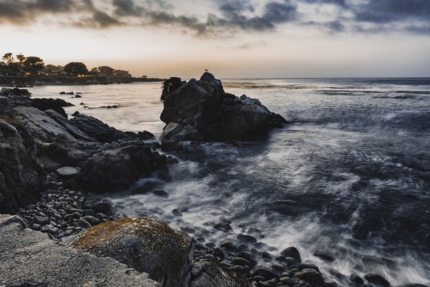 High angle shot of small rocks on the shore of the sea under the cloudy evening sky