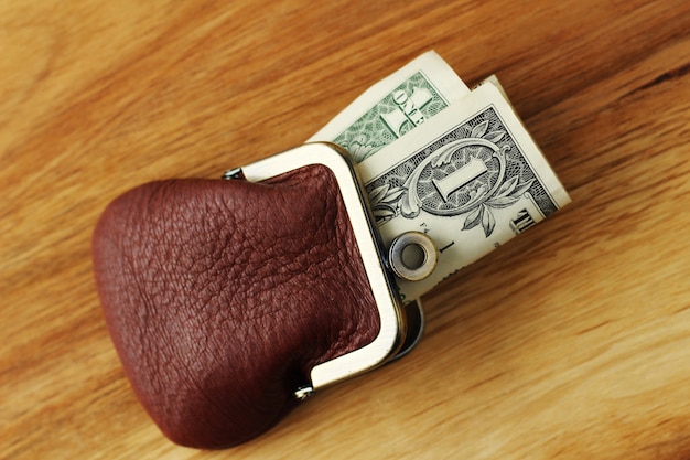 Free Photo high angle shot of some cash in a leather change purse on a wooden surface