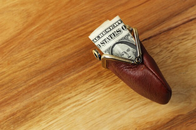 Снимок денег в кожаном портмоне на деревянной поверхности под высоким углом