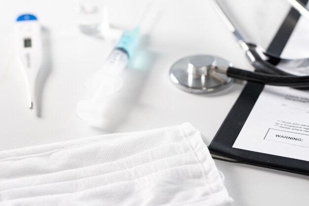 High angle shot of a stethoscope, a syringe, and a bottle of medicine on a piece of paper