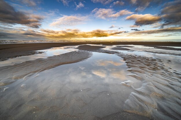 High angle shot of water puddles on the shore with a blue sky