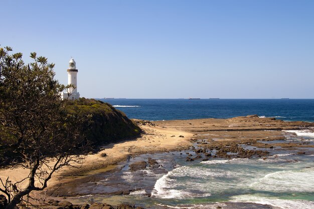 High angle shot of a white lighthouse on the shore of the sea