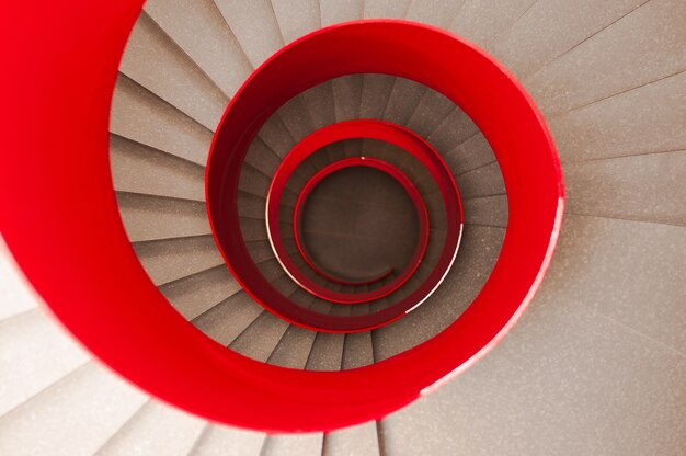 Снимок винтовой лестницы с красными перилами под высоким углом