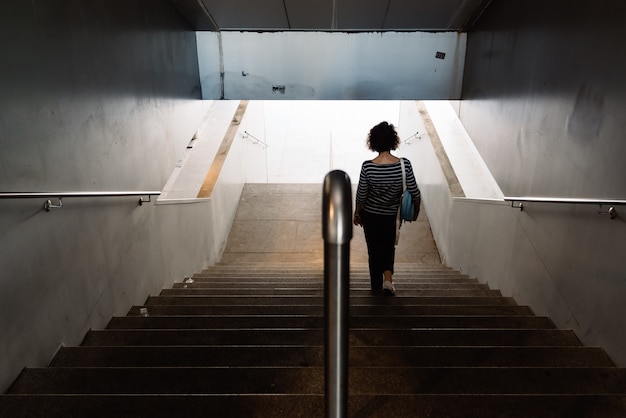 High angle shot of a woman walking down the stairs on an empty staircase