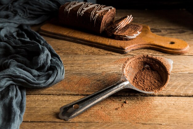 High angle sliced chocolate roll cake and strainer with cocoa powder