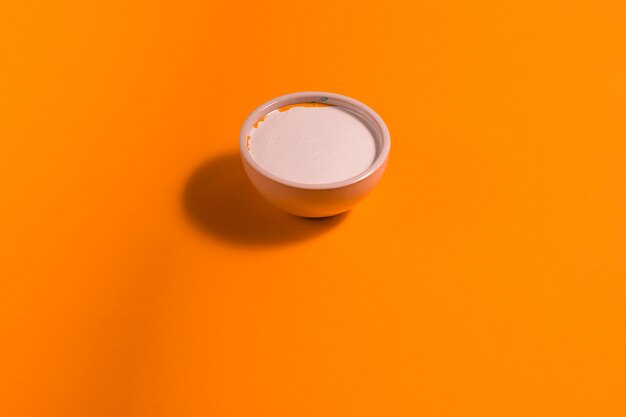 Высокий угол маленькая чаша с краской на оранжевом фоне
