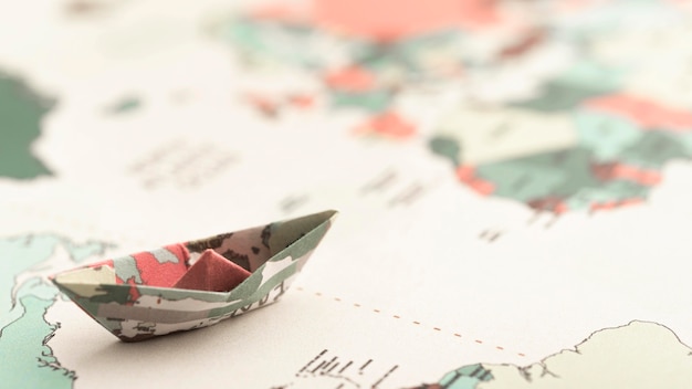 Бесплатное фото Маленькая лодка оригами под высоким углом на карте мира