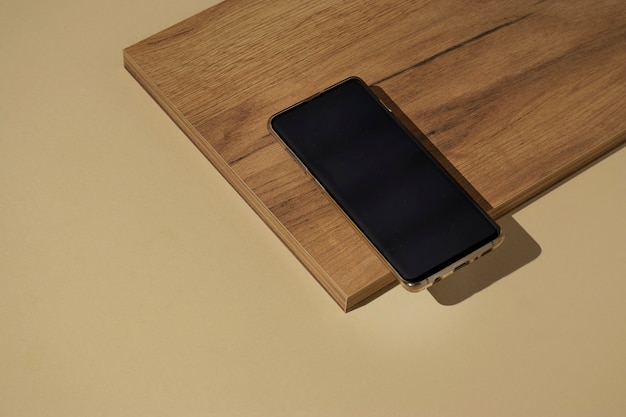 Free photo high angle smartphone on wooden board