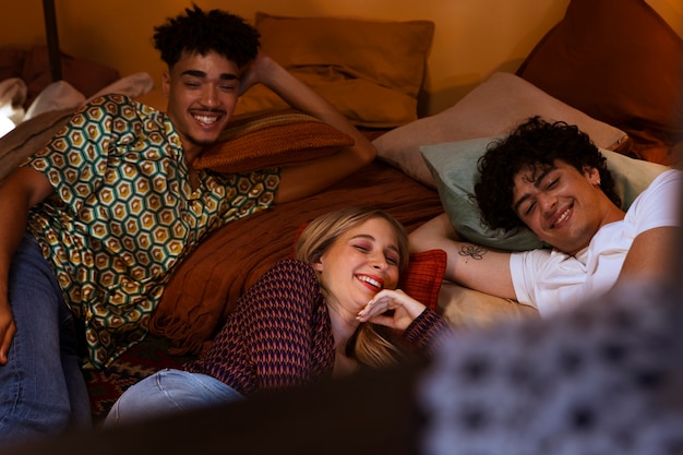 Free photo high angle smiley friends laying in bed