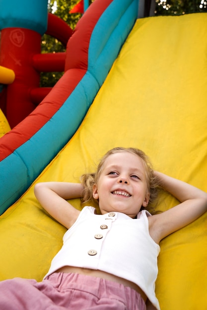 Free photo high angle smiley girl laying in bounce house